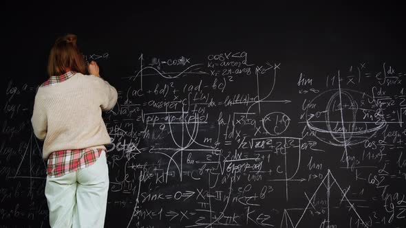 Woman Solves Scientific Problem Writing Formulas on Chalkboard Focused on Studies