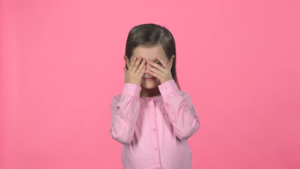 Little Female Is Hiding Face with Hands on Pink Background.