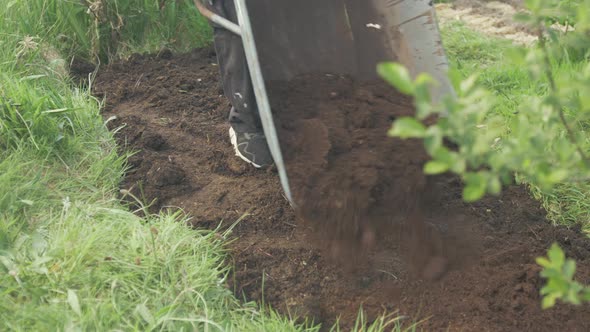 Emptying wheelbarrow of compost over soil for planting