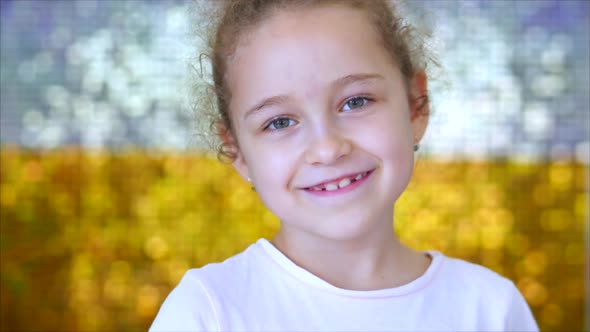 Portrait of a Little Young Girl with Green Eyes Looks at the Camera, Against a Background of White