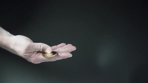 Hand catching falling cryptocurrency coins against black background.