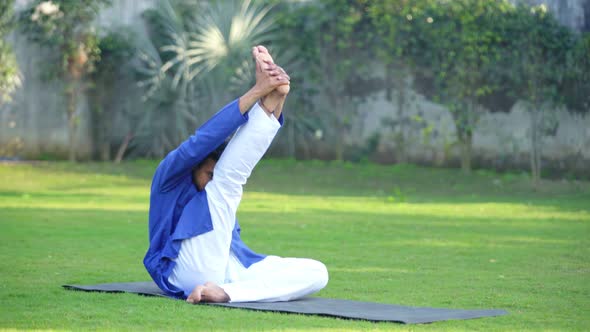 Indian man doing Krounchasana or Heron Yoga Pose in an Indian traditional outfit Kurta Pajama