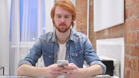 Redhead Beard Man Typing Message on Smartphone SMS or Email