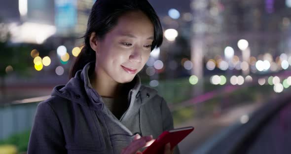 Woman use of mobile phone at night in city