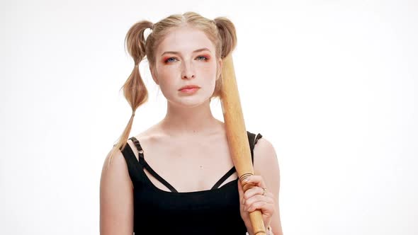 Young Beautiful Girl Looking at Camera Brutally Holding Bat Over White Background