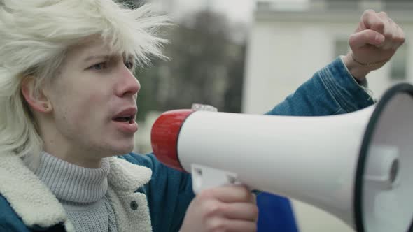 Close up caucasian woman  screaming through megaphone in front and group of people manifesting  in t