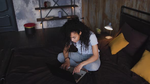 Young Attractive AfricanAmerican Woman Using Laptop Computer in the Bed Dolly Shot High Angle View