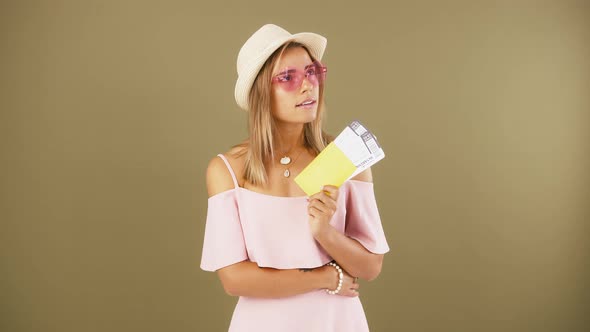 Young Girl in Sunglasses and Hat is Looking at Passport and Tickets in Her Hand Smiling and Looking