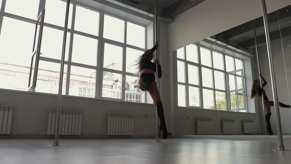 Flexible Woman Dancing on Pole in Studio