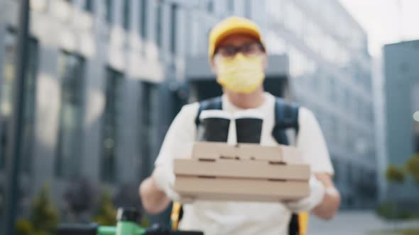 Handsome Delivery Man in Protective Face Mask Holding Stack of Pizza Cardboard