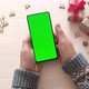 Man holding smartphone with vertical green screen and touch on screen on Christmas background - VideoHive Item for Sale