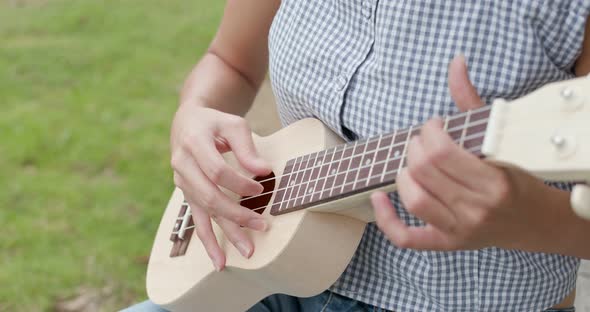 Woman Play a Song on Ukulele and Sitting on The Grass