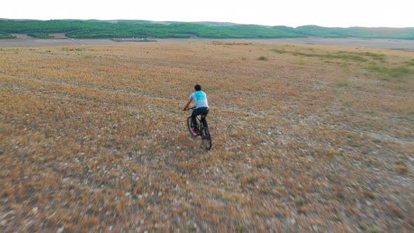 Young man riding a bicycle on countryside. 