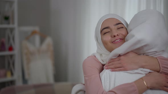 Happy Middle Eastern Bridesmaid in Hijab Hugging Bride Smiling Looking at Camera