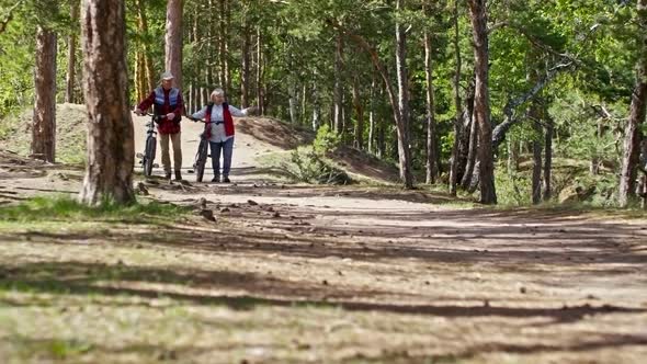 Senior Couple with Bicycles Walking in Forest