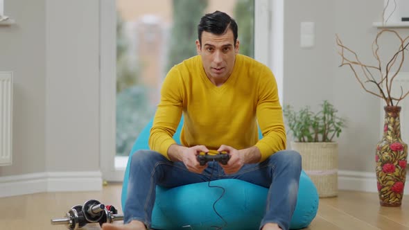 Relaxed Middle Eastern Adult Gamer Using Game Console in Slowmo and Losing in Video Game Making