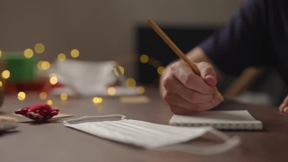 Slow Motion Orbit Shot Closeup Man Writes Shopping List Notepad Pencil Under Warm Light Evening