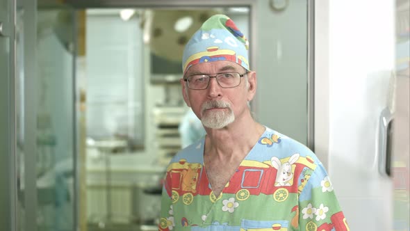 Smiling Senior Doctor Looking at the Camera in Hospital Surgery Examination Room