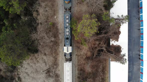 A train engine is stopped just before a bridge over a road.