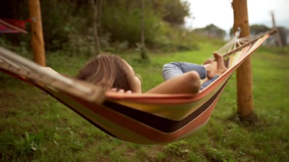 Young Caucasian Female Resting Lying on Hammock Among Two Poles Outdoors in Slowmotion