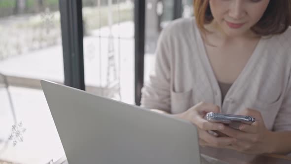 Young woman using smartphone checking social media on the internet in coffee shop, happy smiling.