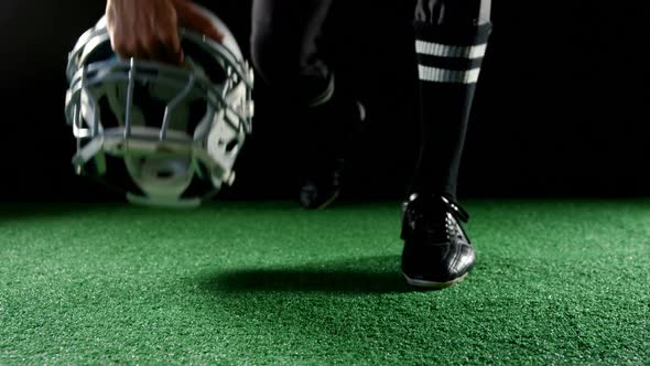 American football player resting his hands on head gear 4k