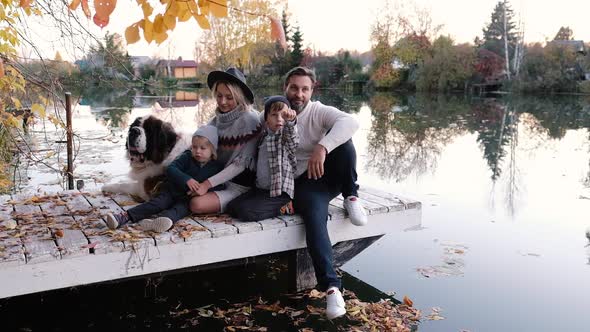 Happy Big Family with Their Dog on a Walk at Sunset Near the Lake on an Autumn Day