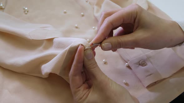 Hands Cutting Button on Blouse Before Dry-cleaning