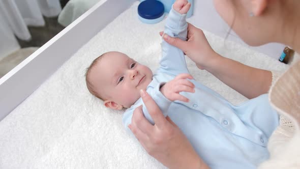 Cute Baby Boy Smiling While Mother Making Gymnastics and Massage on Dressing Table