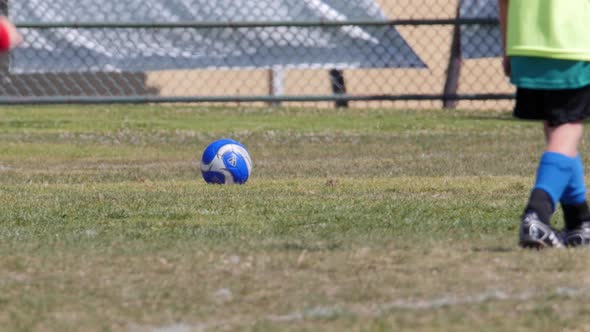 Young boy kicking soccer ball during a youth soccer league game.