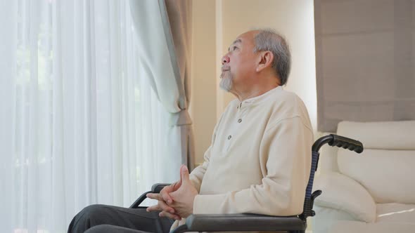 Asian Senior Elderly male sitting alone on wheelchair, feeling lonely stay home after retirement.