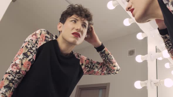 Transgender Man with Makeup Looks in the Mirror Doubtfully