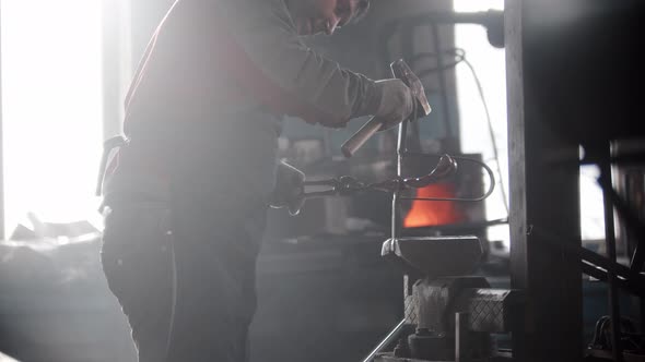 Blacksmith Workshop a Man Works with a Heated Metal Detail in the Pressing Retainer Hits It with a