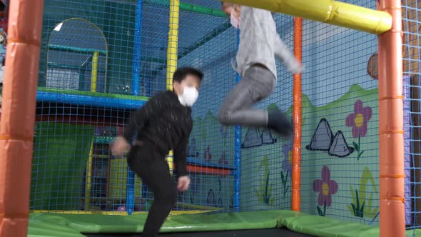 Children with face mask jumping on trampolines in the children's entertainment center.