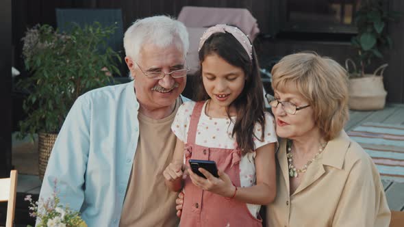 Grandparents Watching Girl Using Gadget