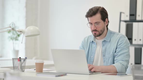 Young Man Working on Laptop in Office