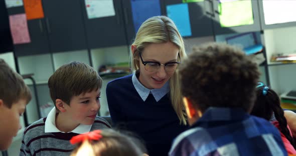 Teacher helping schoolkids with their homework in classroom