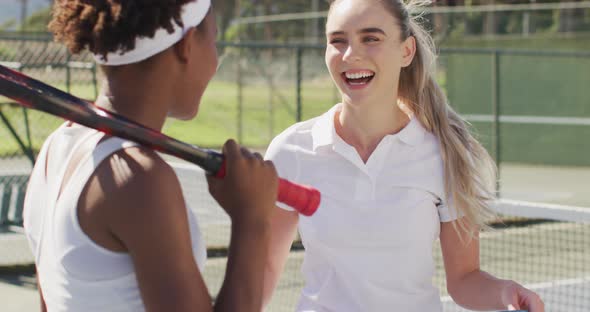 Video of happy diverse female tennis players holding rackets and talking