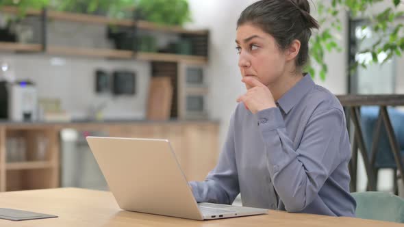 Young Indian Woman Thinking While Using Laptop