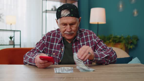 Smiling Senior Man Holding Money Cash and Smartphone Satisfied of Income Planning Family Budget