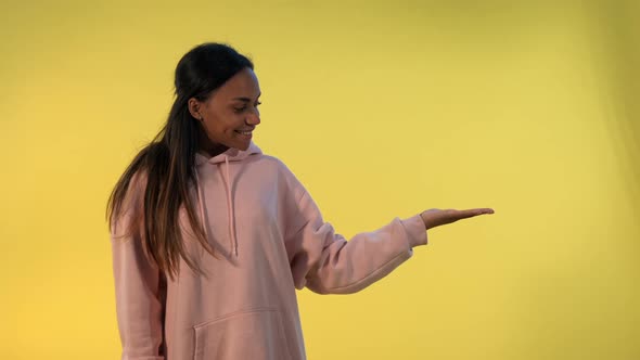 Beautiful African Woman Presenting Something on Empty Hand with Yellow Background