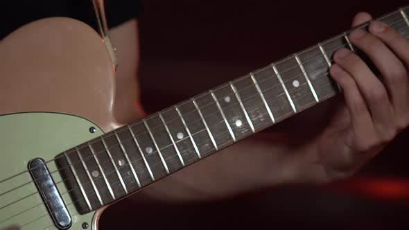 Professional Musician Playing on Electric Guitar in a Dark Studio with Smoke and Neon Lighting