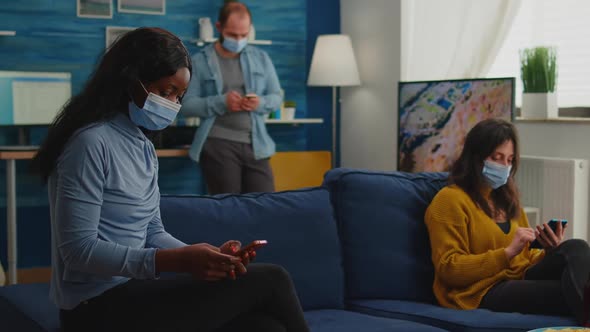 Mixed Racial People Sitting Together in Living Room Browsing on Phones