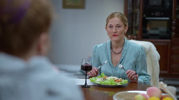 Dissatisfied Wealthy Elegant Lady Sitting at Table with Unrecognizable Hipster Woman Dining