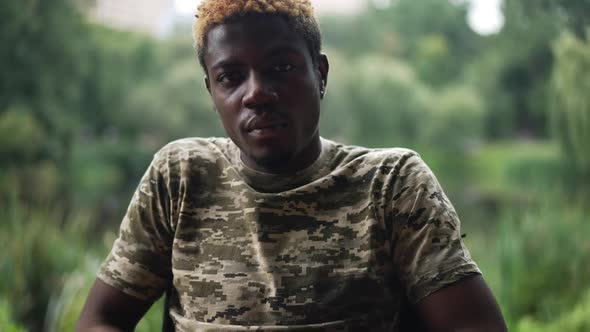 Portrait of Young African American Man in Khaki Tshirt Looking at Camera with Serious Facial