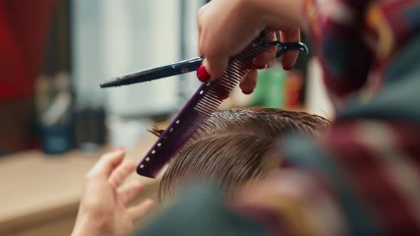 Barbershop, close-up: woman barber cuts men's hair with scissors