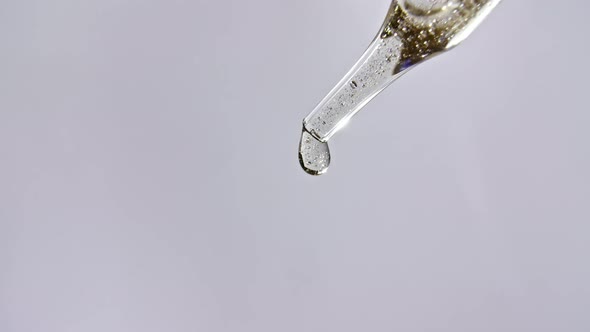Cosmetic Pipette with Drops of Oil Close Up on Gray Background