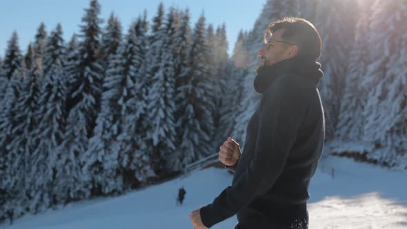 Young Man Dancing, Smiling on a Sunny Winter Day on a Ski Slope in a Snowy Forest Having Fun