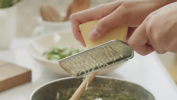 Crop woman grating cheese for pasta