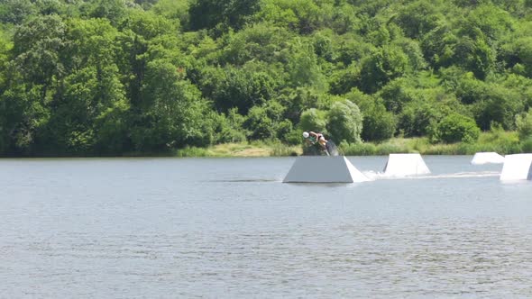 Young Man Jumping on the Ramp with His Wakeboard While Freeriding on a Lake